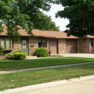 A suburban brick house with a well-maintained lawn and trees.