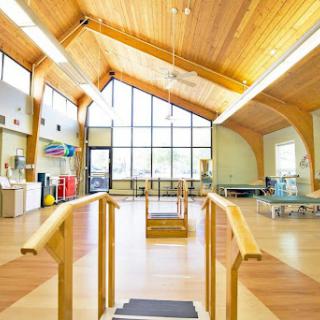 A spacious and inviting rehabilitation center with wooden beams and ample natural light.