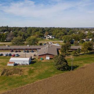 Aerial view of a rural landscape featuring buildings, farmland, and lush greenery.