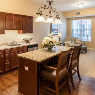 A modern kitchen with wooden cabinets, granite countertops, and elegant lighting.