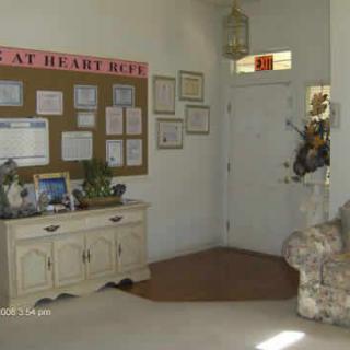 A cozy living room with a bulletin board, decorative furniture, and plants near the entryway.