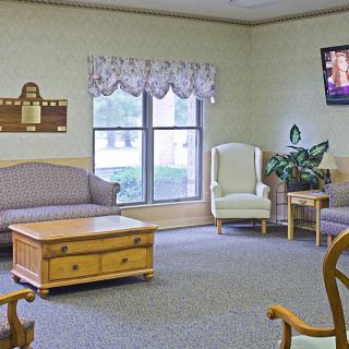 A cozy living room featuring a sofa, armchair, coffee table, and a television mounted on the wall.