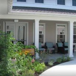 A cozy porch with outdoor seating and a surrounding garden.