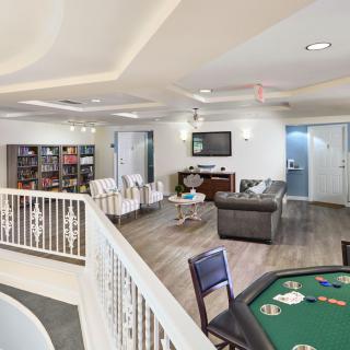 A spacious and modern entertainment room with a seating area and a poker table.