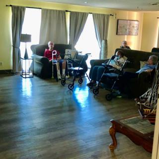 A cozy living room where elderly individuals are seated together, enjoying each other's company.