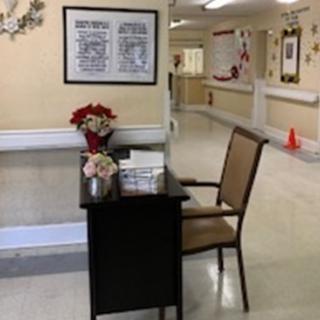 A welcoming waiting area in a healthcare facility, featuring a chair, a small table with flowers, and decorative wall art.
