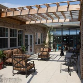 A sunny patio featuring a pergola with outdoor seating and a table.