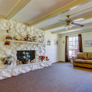A cozy living room featuring a textured fireplace, comfortable couch, and large window with curtains.