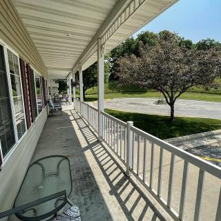 A sunny view of a residential porch with outdoor seating and railings.