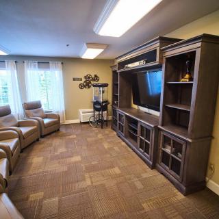 A cozy living room with armchairs and an entertainment center featuring a large TV.