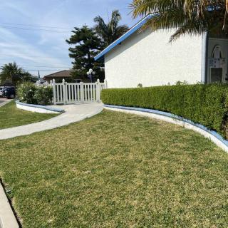 A well-maintained yard with a sidewalk leading to a white fence and house.
