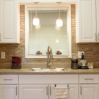 Modern kitchen interior with white cabinets and a central sink.