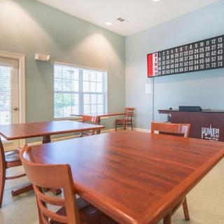 A well-lit community room featuring wooden tables and chairs, perfect for gatherings or meetings.