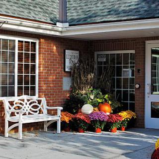A welcoming entrance with a decorative bench and vibrant autumn flowers.