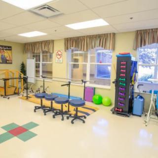 A well-equipped rehabilitation room featuring parallel bars and various exercise equipment.