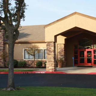 A building entrance with a paved pathway and surrounding greenery.