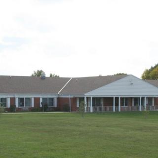 A single-story residential building with a large lawn in front.