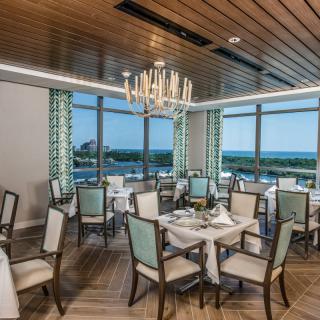 An elegant restaurant dining room with a view of the ocean through large windows.