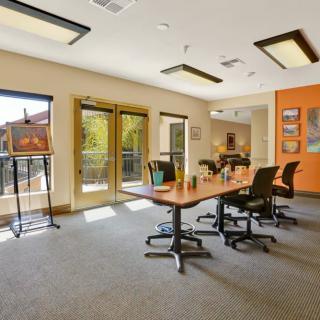 A modern office meeting room with a large conference table, chairs, and abundant natural light.