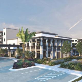 A modern building exterior with a landscaped parking area.