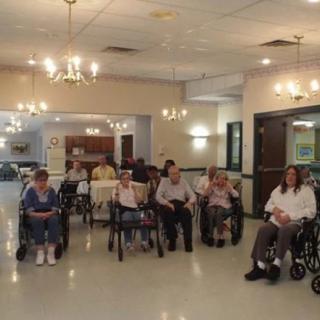 A group of elderly individuals seated in wheelchairs inside a nursing home.