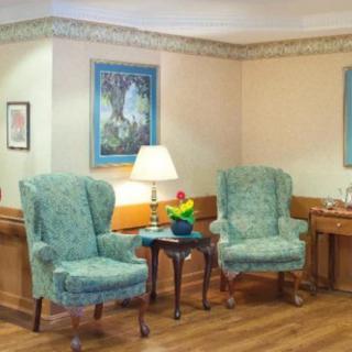 A cozy living room area with two upholstered chairs, a small table, and a lamp.