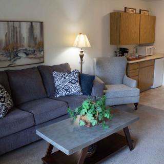 A cozy living room with a sofa, armchair, coffee table, and a lamp.