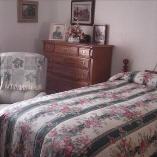 A cozy bedroom with a floral-patterned bedspread and a wooden dresser.
