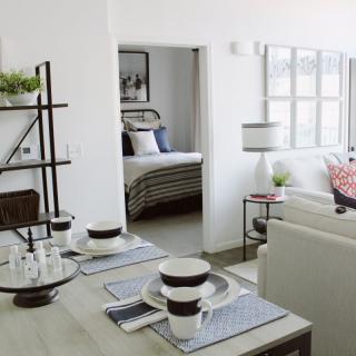 A modern open-concept living space featuring a dining area and view into a cozy bedroom.