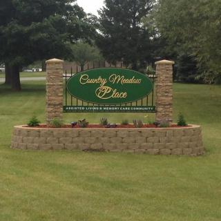 A landscaped area with a sign reading 'County Meadow Place' surrounded by greenery.