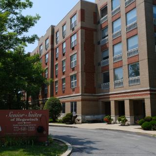 A residential apartment building with a sign and surrounding greenery.