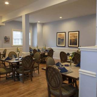 A cozy dining area with neatly arranged tables and chairs, adorned with artwork on the walls.