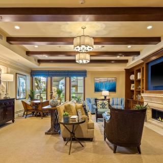 A modern living room with elegant decor, featuring ceiling beams, a fireplace, and stylish furniture.