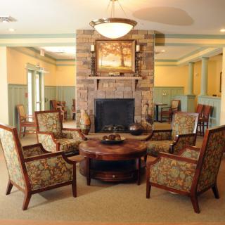 A cozy living room with a fireplace, surrounded by comfortable chairs and a central round table.