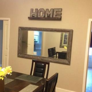 A cozy dining room with a large mirror and decorative 'HOME' sign on the wall.