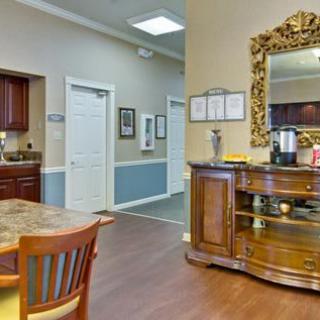 A cozy interior space featuring a wooden cabinet with a large ornate mirror, a dining table with chairs, and a hallway leading to other rooms.