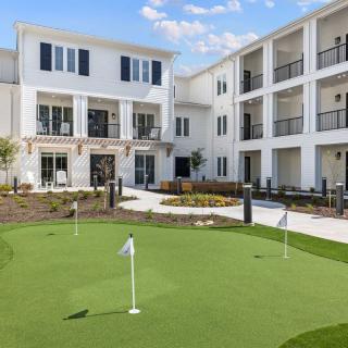 A modern residential building with a well-maintained putting green in the courtyard.