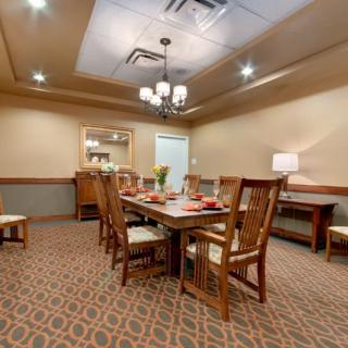 A well-lit dining room with a central table and chairs, featuring elegant interior decor.