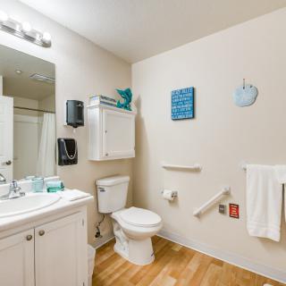 A clean and accessible bathroom equipped with a sink, toilet, and grab bars for safety.