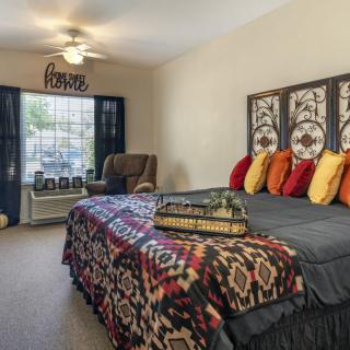 A cozy bedroom featuring a stylish bed with colorful pillows, patterned bedding, and decorative panels as a headboard.