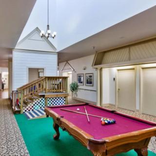 A stylish game room featuring a pool table with a vibrant red cloth, surrounded by decorative interior elements and comfortable lighting.