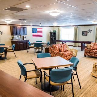 A community recreational room with various seating options and an American flag hanging on the wall.