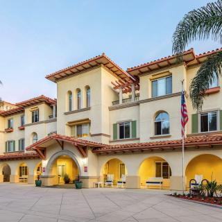 A Mediterranean-style building with large arches and palm trees at the entrance.