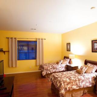A cozy bedroom featuring twin beds with floral bedding and warm yellow walls.