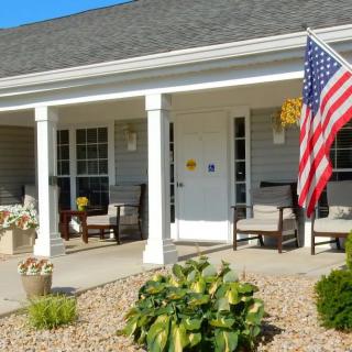 A cozy house porch with chairs and an American flag.