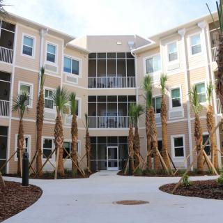 A modern apartment building with palm trees and well-maintained landscaping.