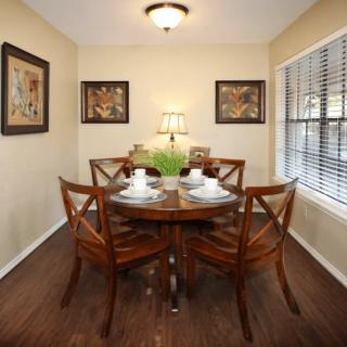 A cozy dining room with a round table set for four, surrounded by artwork and natural light.