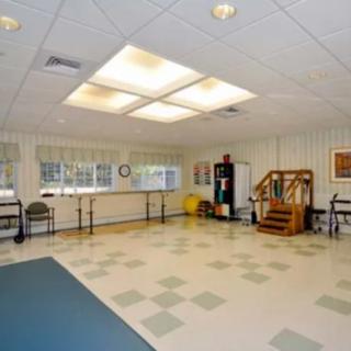 A spacious room designed for physical therapy or exercise, featuring various fitness equipment and a mirrored wall.