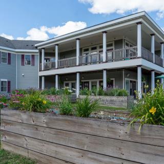 A modern two-story house with a landscaped garden and flower beds.