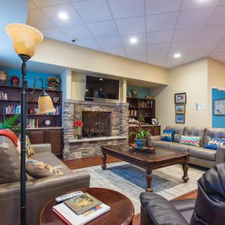 Cozy living room with a fireplace, surrounded by comfortable sofas and bookshelves.